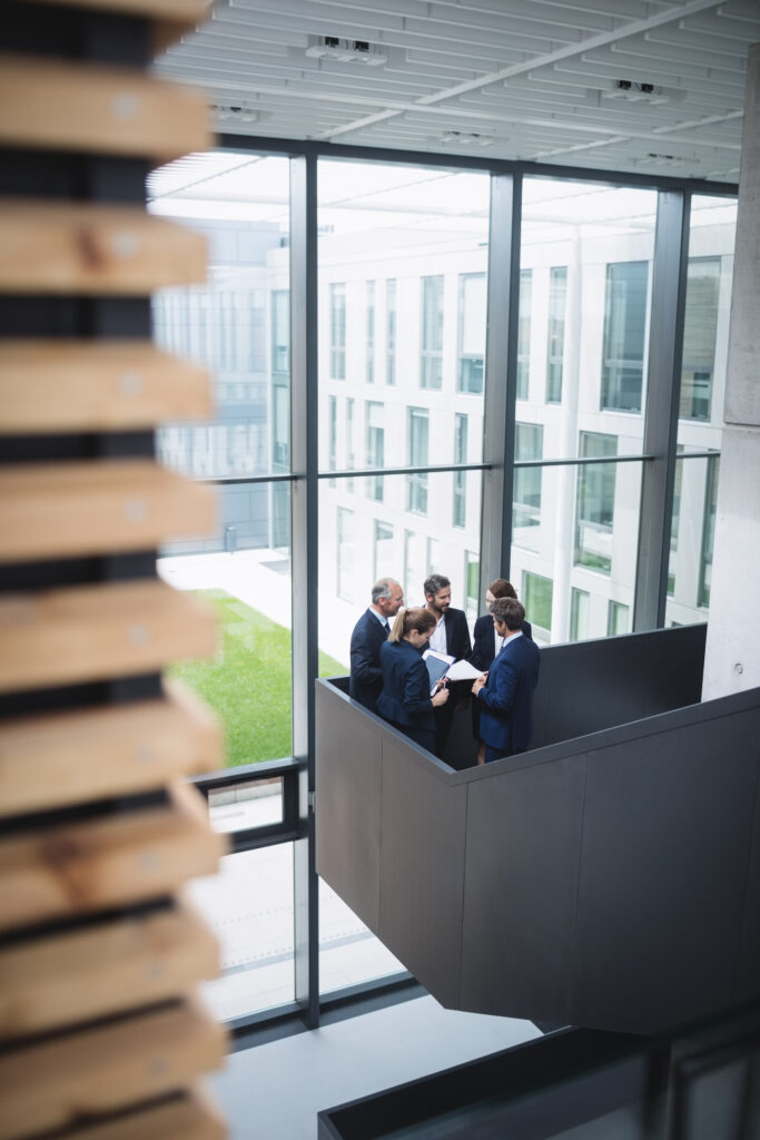 group of businesspeople having a discussion near staircase in office